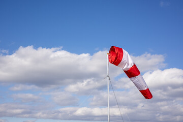 Windsock against a blue sky with clouds.