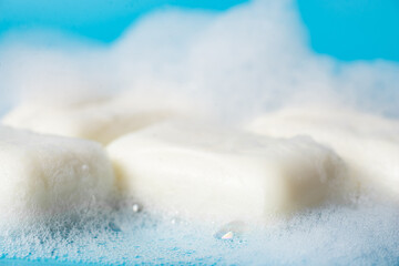 Global Handwashing Day. Hygiene concept, background. Pieces of soap in foam close-up on a light blue background.