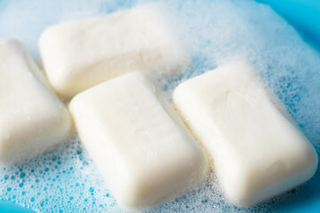 Global Handwashing Day. Hygiene concept, background. Pieces of soap in foam close-up on a light blue background.