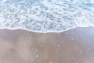 Wave of the sea on sandy beach white foam.Top view of a wave breaking on the sand at the beach. Top view,Copy space.