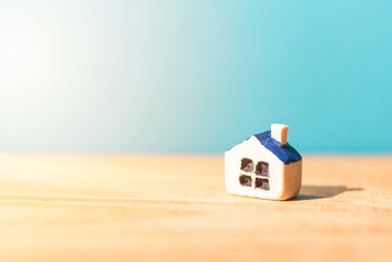 Obraz na płótnie Canvas One miniature toy house on a wooden table on a sunlight.Yellow house model blurred blue background.Copy space.Closeup.