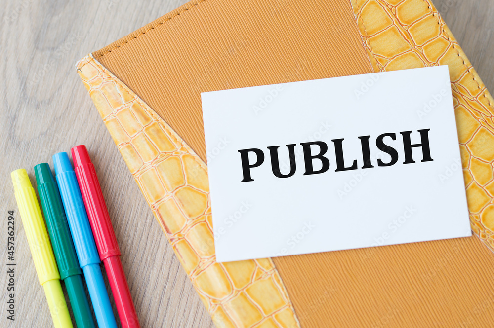 Poster notepad on which the card is with text publish on the on the table next to colored markers