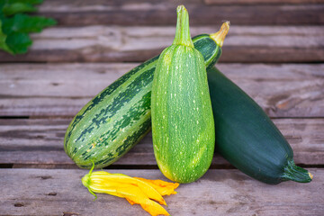 three green zucchini lie on a wooden onet