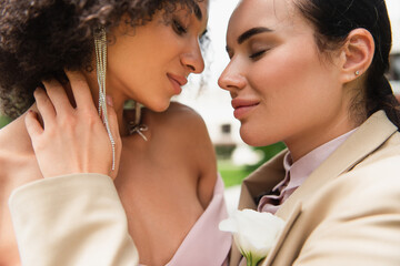 Young woman in suit touching african american girlfriend outdoors.