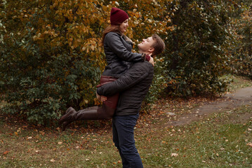 happy loving couple walks in the autumn in the park. A man holds his beloved woman in his arms.
