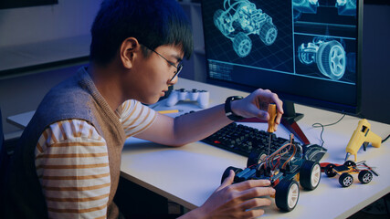 Asian teenager doing Arduino robot homework project in house