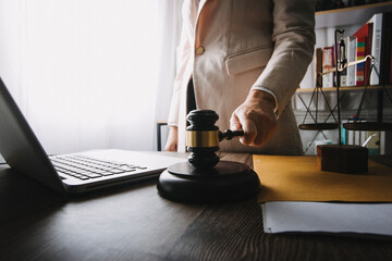Justice and law concept.Male judge in a courtroom with the gavel, working with, computer and docking keyboard, eyeglasses, on table in morning light