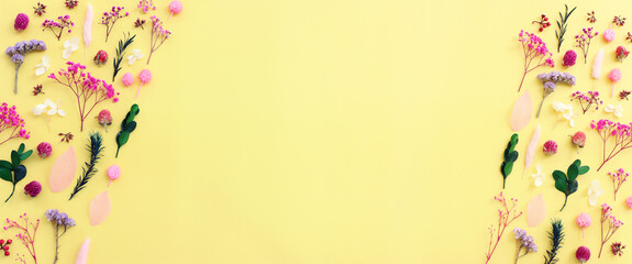 Top view image of pink, purple and green flowers composition over pastel yellow background .Flat lay