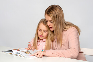Mom helps little daughter to do homework