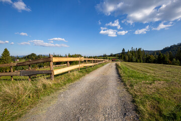 Fototapeta na wymiar Dirt road in the Silesian Beskids, mountain landscape with path along wooden fence