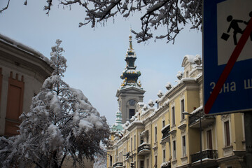 Fototapeta premium Clock tower of Saborna church visible through snowy street branches