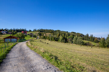 Fototapeta na wymiar Dirt road in the Silesian Beskids, mountain landscape with small village near Wisla in Poland