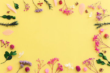 Top view image of pink, purple and green flowers composition over pastel yellow background .Flat lay