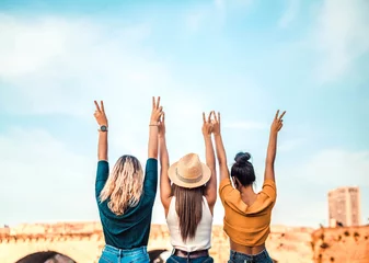 Tuinposter Happy women with arms up outdoors - Female friends having fun on a day around the city - People supporting community - Tourism, travel, freedom and friendship concept © Davide Angelini