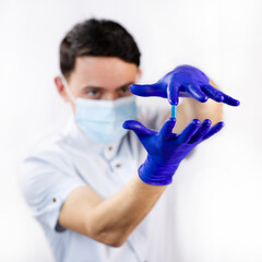 The guy holds the capsule in his hands. The capsule is in the doctor's hand. Blue pill against the virus. Medicines for the disease. A guy in a protective mask and gloves during quarantine.