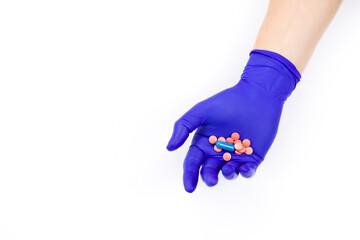 Hand in a protective glove on a white background. A man holds medicines in his hand.  Pills in hand on a white background. Pink pills. Treatment methods. Health care.