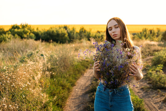Healing Power of Nature, Benefits Of Ecotherapy, Nature Impact Wellbeing. Happy young girl holding wildflowers bouquet, relaxing and enjoying life