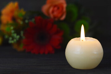 Obraz na płótnie Canvas Burning candle and flowers on dark background. Sympathy card