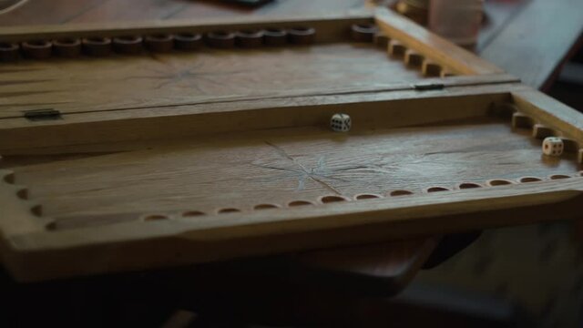 dice fall onto a wooden backgammon board and roll. the game starts. slow motion