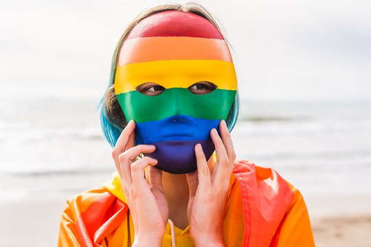 Masked person with authentic hand painted LGBT mask on the beach