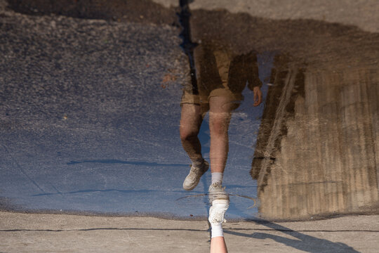 Reflection of a girl running in a puddle