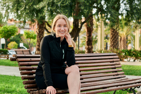 Portrait of a young blonde woman smiling at the camera in a park