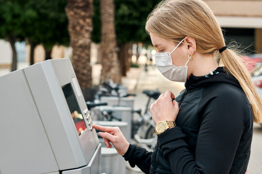 Young woman in sportswear prepares to pay for a rental bike in a city