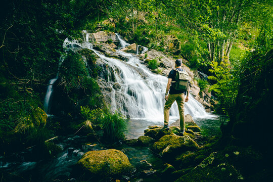 Man exploring with backpack in a waterfall