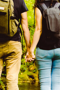 Couple with backpack in forest holding hands