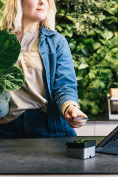Employee accepting RFID chip payment of credit card at plant store