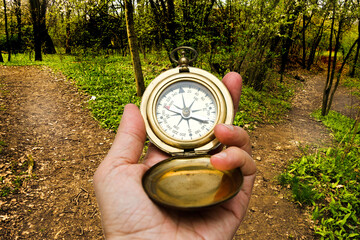 hand holding a compass in front of a crossroad, choosing a direction concept