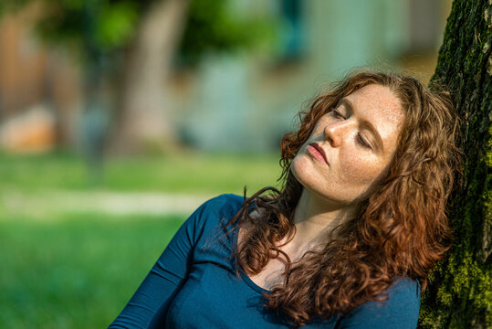 Portrait of charming redhead young woman with freckles enjoying sun
