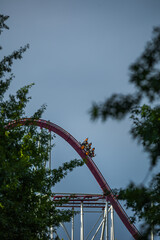 The train with some people is riding on roller coaster during a cloudy weather