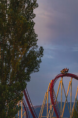 The train with some people is riding on roller coaster during the sunset