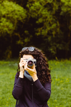 Dark-haired woman taking photos in the forest