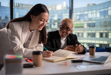 Positive diverse businesswoman making notes in office