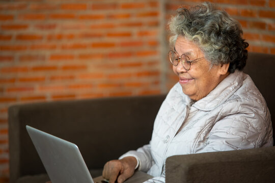 Smiling senior woman wave to camera having video call on laptop,
