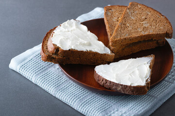 Rye bread with cream cheese on wood plate, rustic food