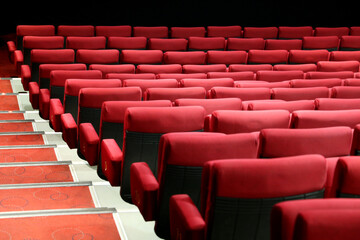 Empty cinema hall with red seats and stairs. Interior of movie theatre, selective focus