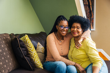 Portrait of smiling senior woman with daughter sitting on sofa at home