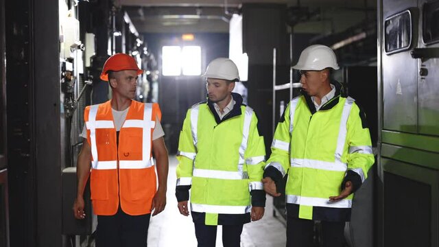 Group of smart three engineer team with perfect safety uniform brainstorming idea planning to control project of industry. They work at the electric power factory