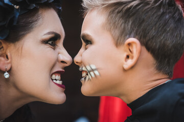side view of mother and son in spooky makeup grinning at each other