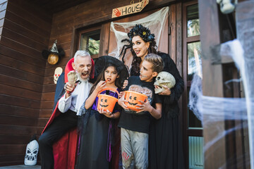 man holding toy hand and grimacing near family in halloween costumes