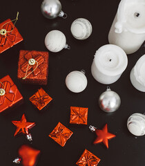 Christmas decorations, bows, candles, gifts, bells in red and white colors on black background. Holiday and celebration. Flat lay, top view
