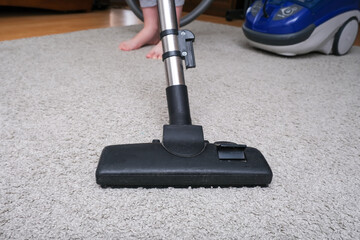 A person vacuuming the carpet in the house, cleaning rug with the vac concept