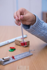 Close-up of a physical pendulum in a student's hand. A schoolboy performs a task at the workplace. The concept of children's education, teaching knowledge, skills and abilities.