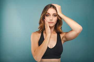 Young Woman with Blue Eyes and Brown Hair poses before a Blue Background