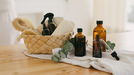 Kitchen interior with natural eco-friendly zero waste plastic free cleaning items: brushes, rugs, soap, essential oils, spray and sponges in a wicker basket.