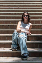 Confident female student on college campus relaxed while sitting on the steps