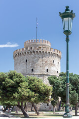 Fototapeta na wymiar Byzantine heritage White Tower in Thessaloniki with trees in front and a lamp post in the foreground